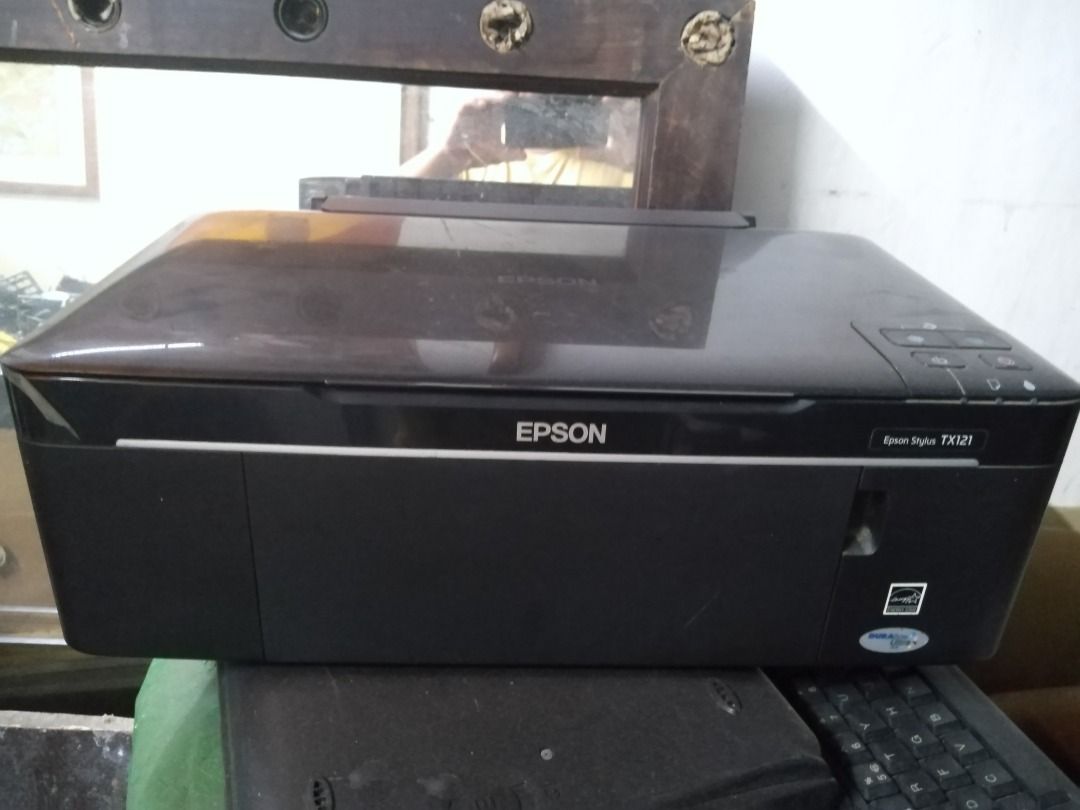 Epson Stylus TX121 Printer (Category: Printers, Scanners & Copiers) located in Manila. Submitted by maybonifacio (Listing ID 1430684385, Image 2). Description: Epson Stylus TX121 printer. The printer is black and has the Energy Star label. It has a flatbed design. The model name is visible on the front of the printer..