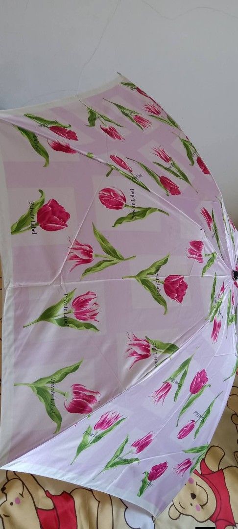 Floral Print Umbrella private label (Category: Umbrellas) located in Gapan. Submitted by montesnora80204 (Listing ID 1430652687, Image 2). Description: Umbrella features a beautiful floral print. It has a pink and white color scheme with a tulip design. The umbrella is foldable and has a handle with a strap. The brand is Private Label. It is a stylish and practical accessory for rainy days..