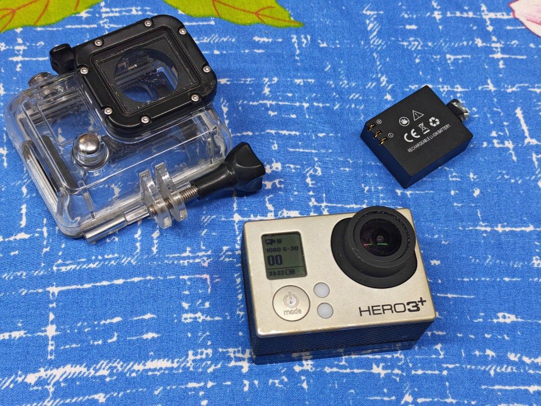 GoPro HERO3+ Action Camera (Category: Cameras) located in Manila. Submitted by ultimogizmos (Listing ID 1430614196, Image 1). Description: GoPro HERO3+ action camera with a waterproof housing, battery, and mounting hardware. The camera has a silver body with a black lens and buttons. The waterproof housing is clear with black accents. Includes a battery and a mounting screw. unit with 1 extended battery and 1 ordibary battery memory case no issue
