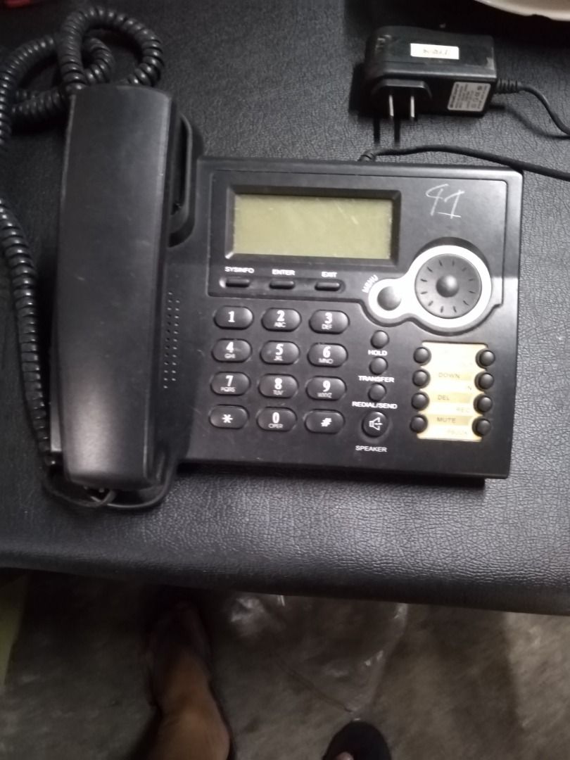 IP Phone voip (Category: iPhone 6 Series) located in Manila. Submitted by maybonifacio (Listing ID 1430686590, Image 1). Description: Black IP phone with a display screen and multiple buttons. Features include hold, transfer, and speakerphone functions. The model is an IP Phone, with WAN: DHCP and LAN: 192.168.10.1. Includes a power adapter. Suitable for home or office use..