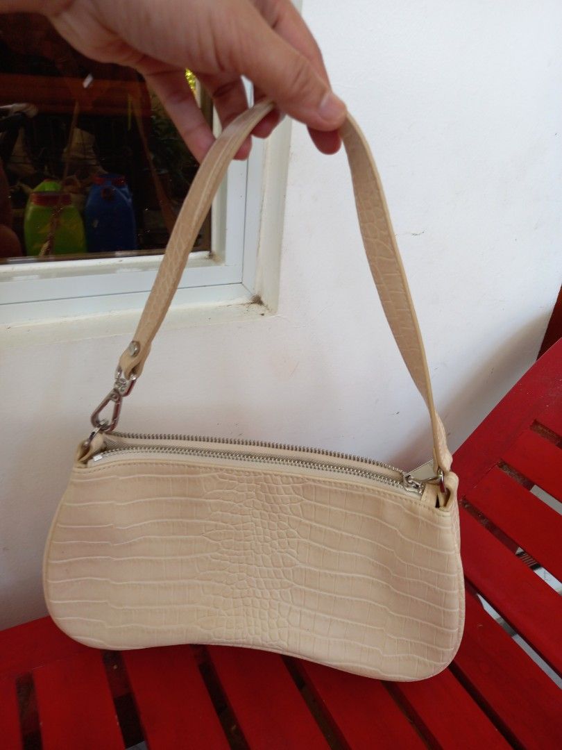 JW PEI Croc-Embossed Shoulder Bag (Category: Shoulder Bags) located in Tuguegarao City. Submitted by zenphoenix-7ad615 (Listing ID 1430643299, Image 3). Description: Shoulder bag features a unique, curved design with a croc-embossed finish. It has a zipper closure and a single shoulder strap. The interior includes a small pocket and a JW PEI label. The bag is in a light beige color. 10.5 by 5 inches.