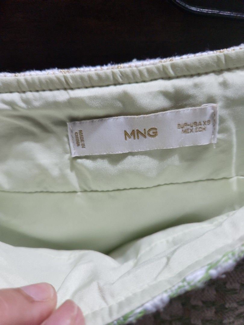Mango Green and White Tweed skirt (Category: Blouses) located in Makati City. Submitted by fairytale8888 (Listing ID 1430726699, Image 2). Description: Authentic Top from MNG features a textured green and white pattern. The inside lining is a light green color. The tag indicates it is made in China. The fabric has a woven appearance..