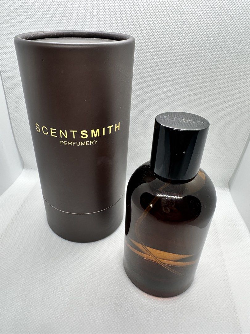 Scentsmith Perfumery 828 Banyan Eau de Parfum 100ml (Category: Fragrance & Deodorants) located in Taguig. Submitted by heytreasure (Listing ID 1430609023, Image 2). Description: Bottle of Scentsmith Perfumery 828 Banyan Eau de Parfum. The perfume comes in a brown glass bottle with a black cap and a cylindrical brown box. The box has the brand name "Scentsmith Perfumery" printed in gold. The label on the bottle indicates it is composed for "Banyan