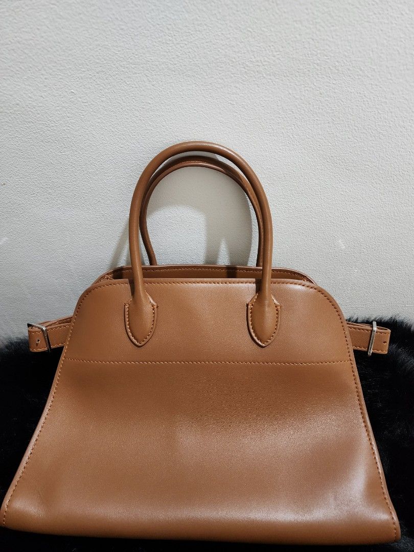 The Row - Margaux in Classic Brown (Category: Luxury Bags & Wallets) located in Cebu City. Submitted by avapaluca (Listing ID 1430771955, Image 1). Description: Beautiful leather handbag from The Row. Features a top handle design with an additional shoulder strap. The bag has a spacious interior with a zippered pocket. The exterior is a rich brown color with detailed stitching. The Row logo is visible on the interior and exterior hardware. Made i