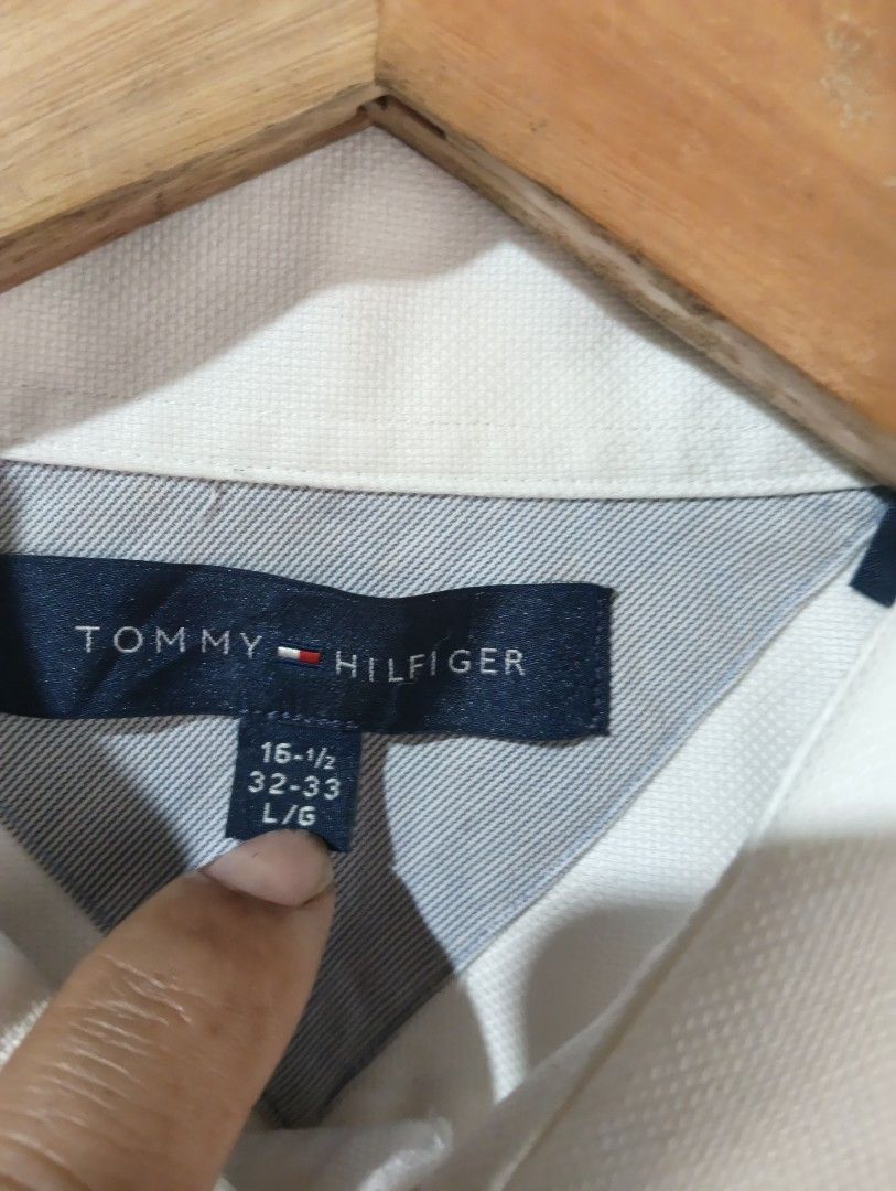 Tommy Hilfiger White Long Sleeve Shirt (Category: Tshirts & Polo Shirts ) located in Davao. Submitted by noelamihan05424 (Listing ID 1430659934, Image 3). Description: Classic white long sleeve shirt from Tommy Hilfiger. Features a button-down front, a chest pocket, and buttoned cuffs. The label indicates a size of 16-1/2 and a sleeve length of 32-33. Made in Bangladesh. Includes care instructions on the tag. Excellent to like new condition Authe