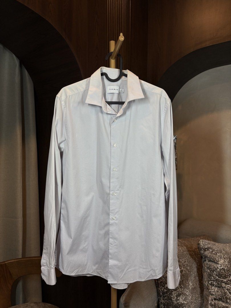 Topman Long Sleeve Shirt - Size M (Category: Tshirts & Polo Shirts ) located in Manila. Submitted by ccuadralaw (Listing ID 1430678160, Image 1). Description: Topman long sleeve shirt in a light grey color. It features a classic collar and button-down closure. The shirt is size M and made in Bangladesh. It is made of 64% Polyester and 4% Elastane. The care label indicates it can be machine washed..