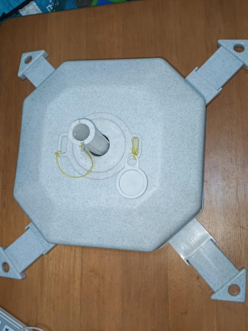 Umbrella Base (Category: Umbrellas) located in Caloocan City. Submitted by surplusandbnewshop (Listing ID 1430646827, Image 1). Description: - Sturdy umbrella base for outdoor use. - Octagonal design with four supporting legs for stability. - Includes a central pole holder and removable cap. - Made of a speckled, light-colored material. - Designed to securely hold a standard umbrella pole. - Easy to set up and use..