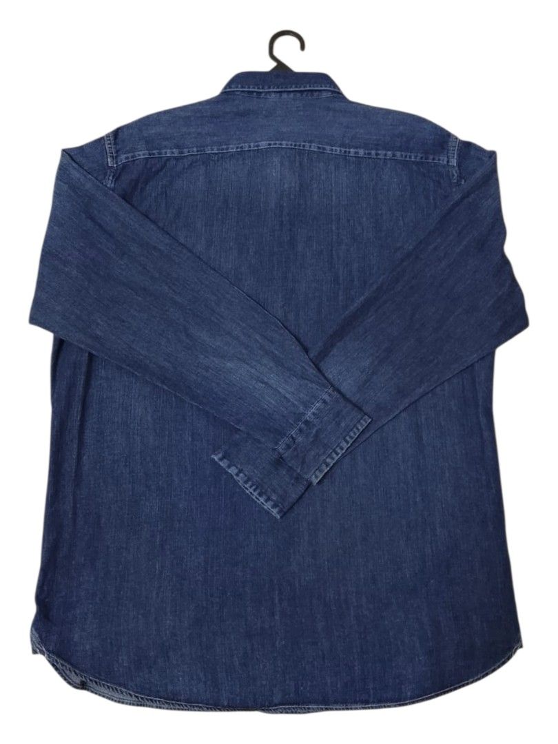Uniqlo Denim Shirt XL (Category: Formal Shirts) located in Lunas. Submitted by znz_collections (Listing ID 1430604467, Image 3). Description: Uniqlo denim shirt in size XL. Features a classic button-down design with two chest pockets. The shirt is a dark blue denim color. Made in Bangladesh. The shirt has long sleeves and a standard collar. The tag indicates the shirt is a size XL. Size XL Pit to Pit : 24 inches Length : 30 inches.