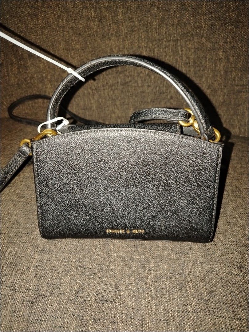 Charles & Keith Black Handbag (Category: Luxury Bags & Wallets) located in Munoz. Submitted by makie_ukay (Listing ID 1430936184, Image 2). Description: Black handbag from Charles & Keith. Features a top handle and a detachable shoulder strap. The bag has a rectangular shape with a gold-tone clasp closure. The brand name is visible on the front and inside the bag. Includes a zipper pocket inside..