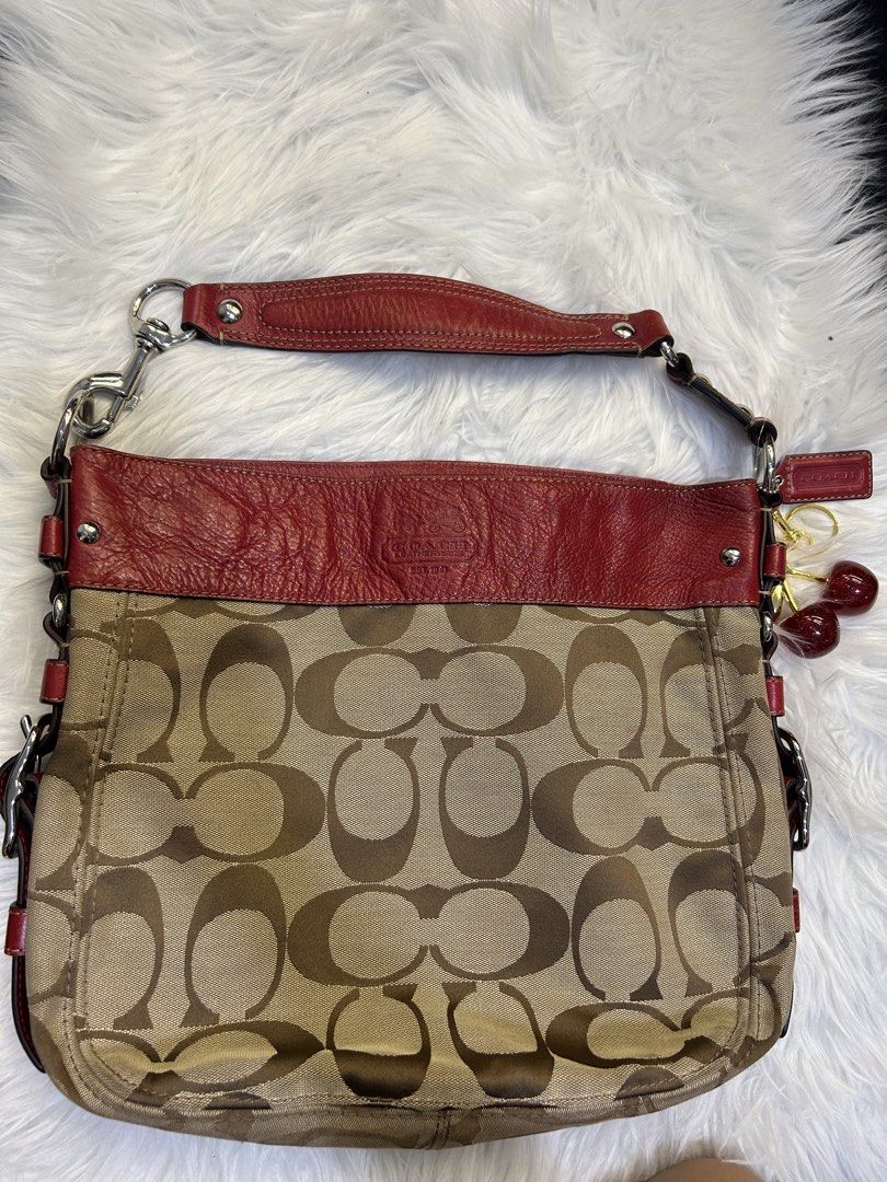 Coach Signature Hobo Bag (Category: Luxury Bags & Wallets) located in Manila. Submitted by graceyabut0 (Listing ID 1430890606, Image 1). Description: Coach signature hobo bag with red leather trim and accents. Features a classic Coach pattern in a neutral color. Includes a detachable cherry charm. The interior has multiple compartments. The bag has a shoulder strap and silver-tone hardware. The bag has a Coach tag attached..