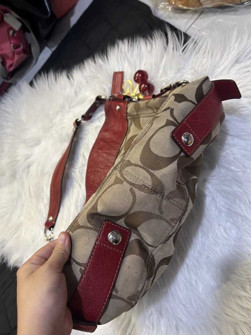 Coach Signature Hobo Bag (Category: Luxury Bags & Wallets) located in Manila. Submitted by graceyabut0 (Listing ID 1430890606, Image 3). Description: Coach signature hobo bag with red leather trim and accents. Features a classic Coach pattern in a neutral color. Includes a detachable cherry charm. The interior has multiple compartments. The bag has a shoulder strap and silver-tone hardware. The bag has a Coach tag attached..