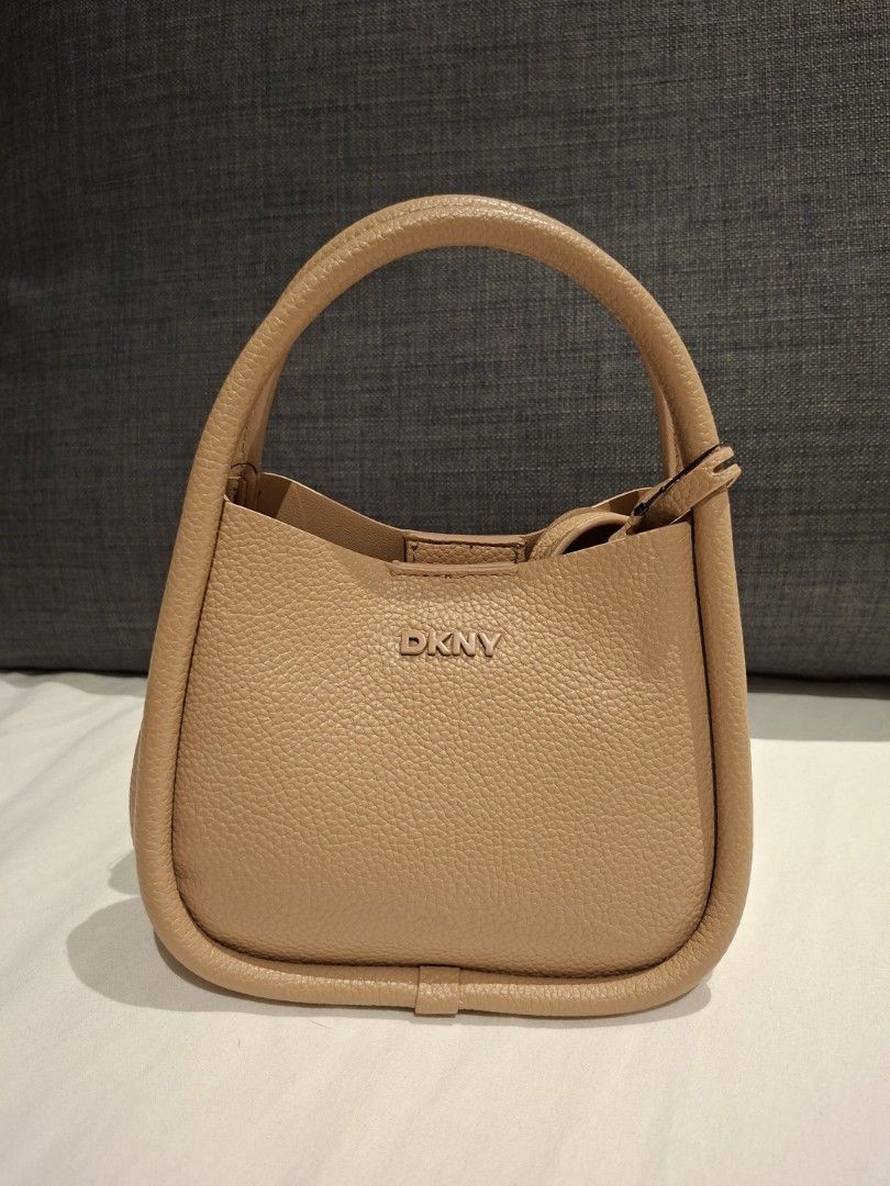 DKNY Capri Hobo Crossbody Bag (Category: Cross-body Bags) located in Makati City. Submitted by jacky222323 (Listing ID 1430924570, Image 1). Description: From US Bnew - DKNY Capri Hobo crossbody bag - Tan color - Top handle and detachable shoulder strap - Main compartment with zippered pouch - DKNY logo on front - Original price tag attached: $138 MSRP.
