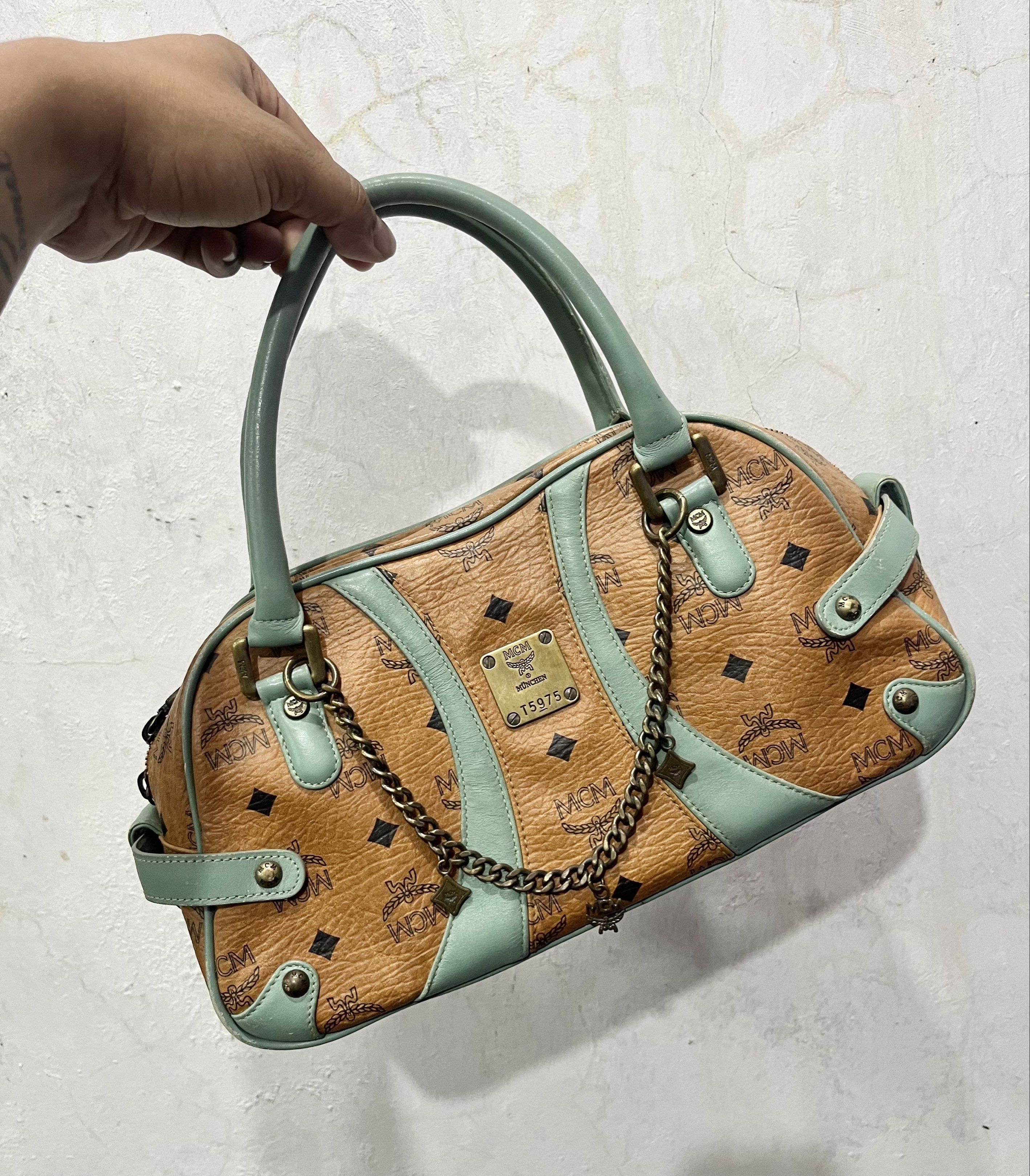 MCM Authentic Visetos Boston Bag (Category: Luxury Bags & Wallets) located in General Trias. Submitted by zrchustle.604 (Listing ID 1430920612, Image 1). Description: MCM Visetos Boston Bag in the Cognac and Light Turquoise colorway. This specific vintage style features MCM's signature Visetos monogram on cognac-colored coated canvas, accented by turquoise leather trim and handles. Key Product Details: Design: A classic satchel or "Boston" silhou