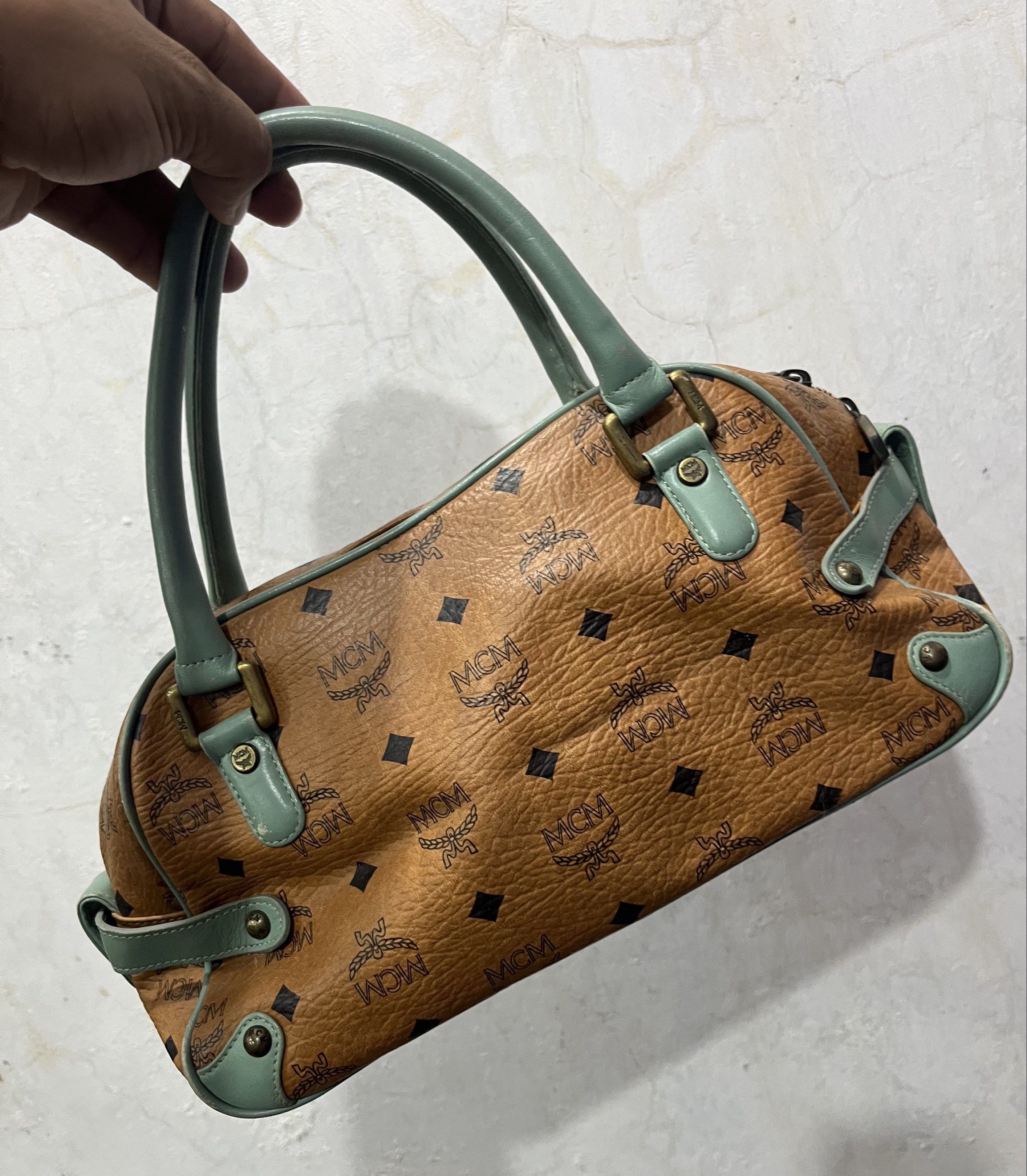 MCM Authentic Visetos Boston Bag (Category: Luxury Bags & Wallets) located in General Trias. Submitted by zrchustle.604 (Listing ID 1430920612, Image 3). Description: MCM Visetos Boston Bag in the Cognac and Light Turquoise colorway. This specific vintage style features MCM's signature Visetos monogram on cognac-colored coated canvas, accented by turquoise leather trim and handles. Key Product Details: Design: A classic satchel or "Boston" silhou