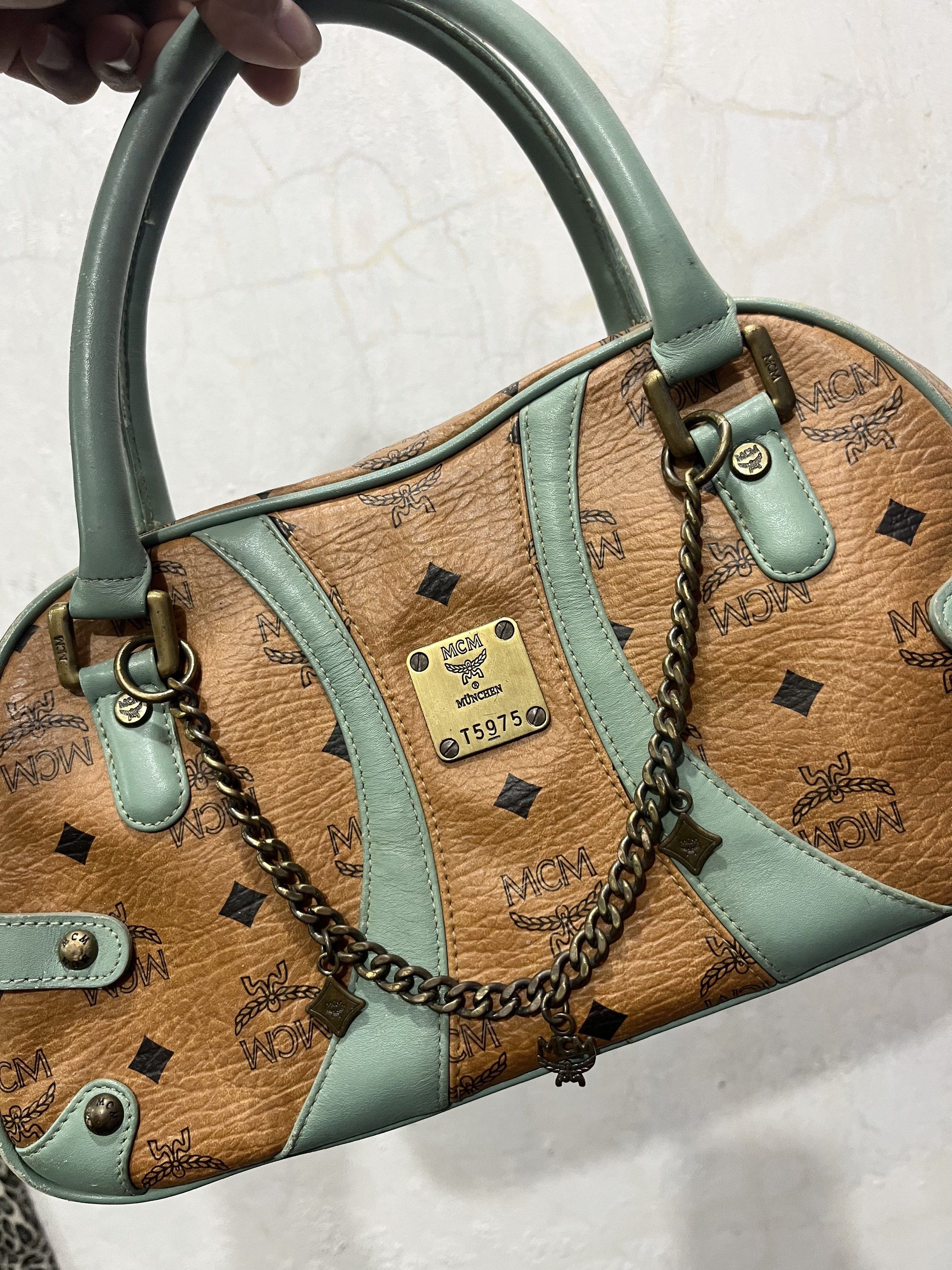 MCM Authentic Visetos Boston Bag (Category: Luxury Bags & Wallets) located in General Trias. Submitted by zrchustle.604 (Listing ID 1430920612, Image 2). Description: MCM Visetos Boston Bag in the Cognac and Light Turquoise colorway. This specific vintage style features MCM's signature Visetos monogram on cognac-colored coated canvas, accented by turquoise leather trim and handles. Key Product Details: Design: A classic satchel or "Boston" silhou