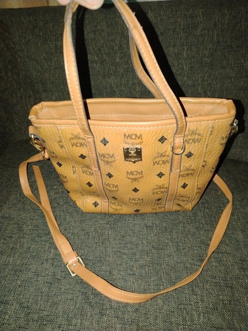 MCM Visetos Small Tote Bag (Category: Luxury Bags & Wallets) located in Munoz. Submitted by makie_ukay (Listing ID 1430935829, Image 1). Description: MCM Visetos Small Tote Bag with a detachable shoulder strap. Features the iconic MCM logo pattern. The bag has a top handle and a zip closure. The interior includes a small pocket with the MCM logo. The hardware is gold-toned..
