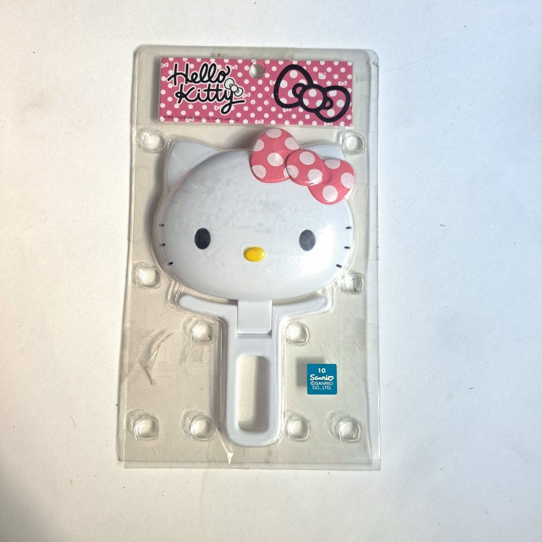 Original Sanrio Hello Kitty Handheld Mirror (Category: Mirrors) located in M'Lang. Submitted by ardinelle.finds (Listing ID 1430858770, Image 1). Description: Kitty handheld mirror. It features a white frame with Kitty's face and a pink bow. The mirror is in its original packaging. The back of the packaging has Japanese text. It has a handle for easy use..