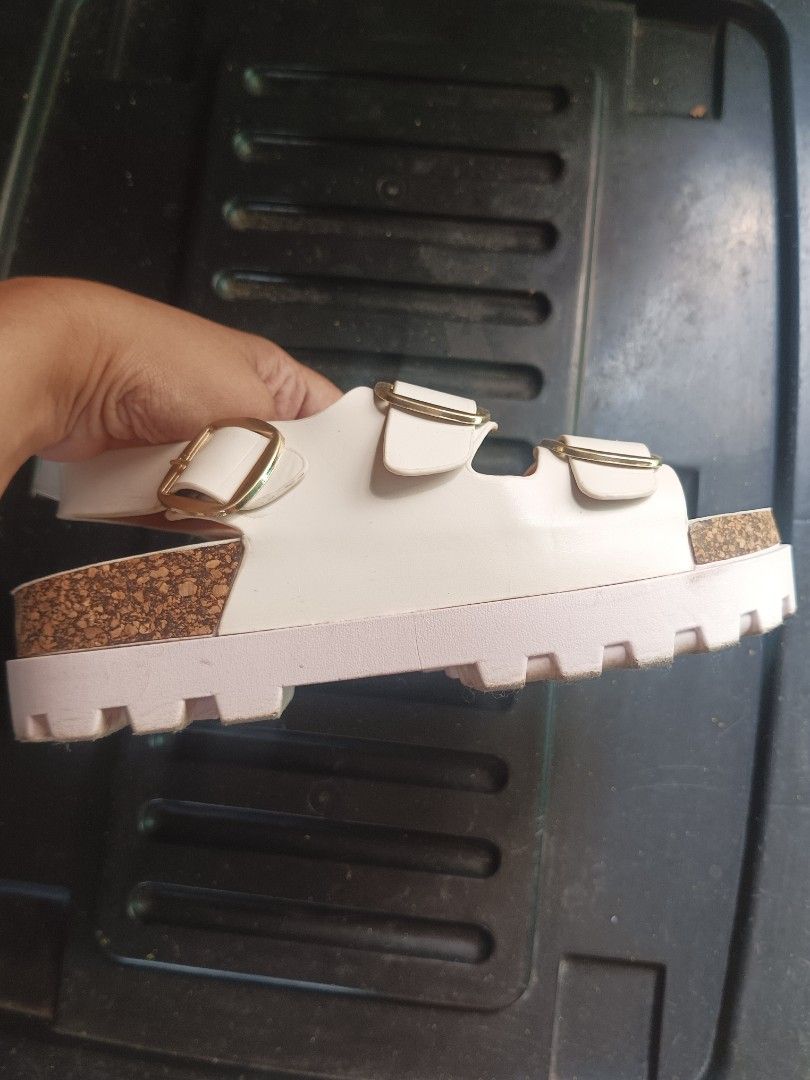 Sorores White Sandals Size 37 (Category: Flats & Sandals) located in Malabon City. Submitted by mslalan (Listing ID 1430806414, Image 3). Description: White Sorores sandals with double buckle straps. The sandals have a cork-like footbed and a thick, white sole. The size is 37, as indicated on the sole. The soles show some signs of wear. The sandals have gold-colored buckles..
