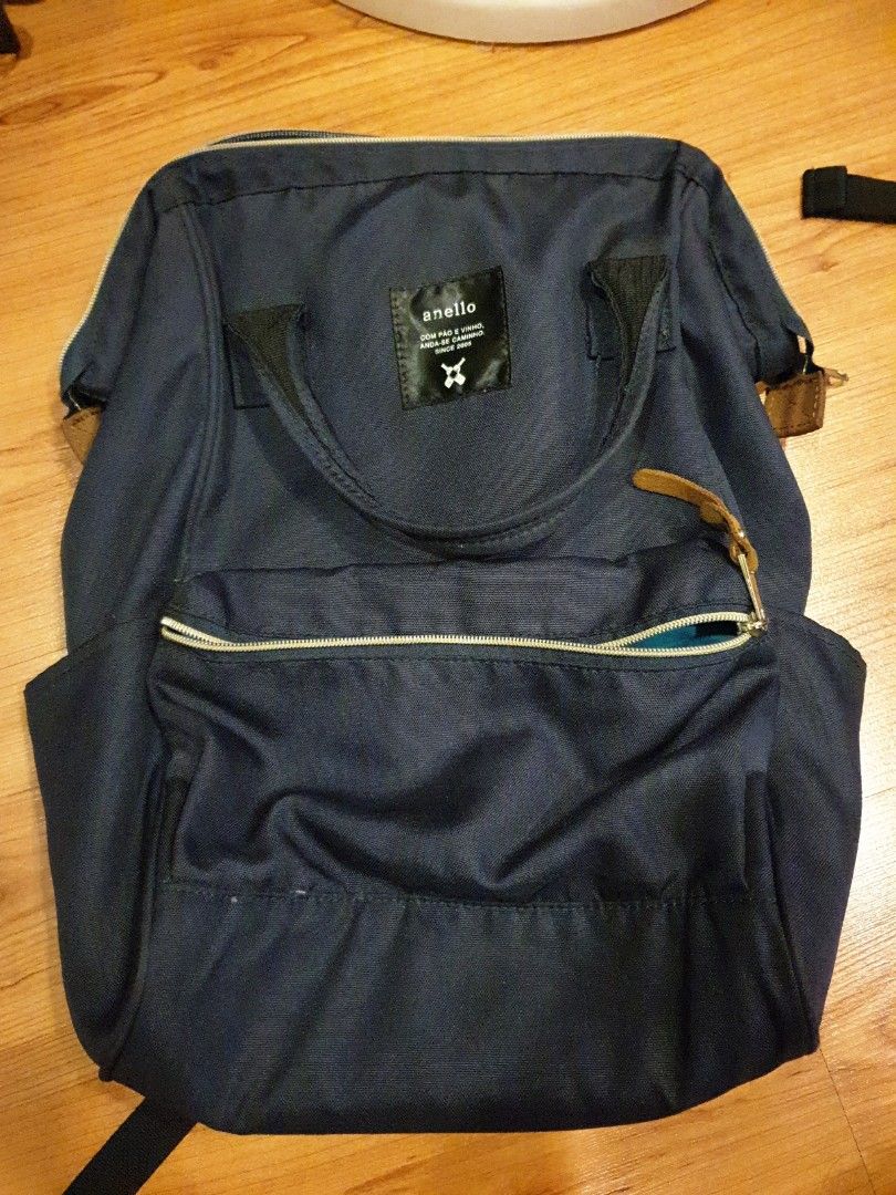 Anello Backpack - Navy Blue (Category: Backpacks) located in Quezon City. Submitted by aredattic (Listing ID 1431067725, Image 1). Description: Navy blue Anello backpack. The interior is teal. Features a top handle and adjustable shoulder straps. Includes a front zipper pocket, 2 side pockets, and a main compartment zipper. The backpack has a small brand tag on the front. flaws: softened bag structure RFS: decluttering.