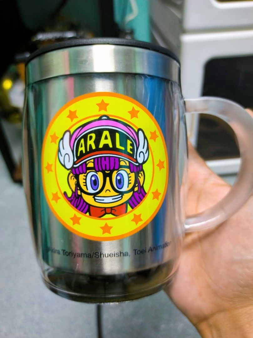 Arale Stainless Steel Mug with Lid (Category: Coffee & Tea Tableware) located in Caloocan City. Submitted by greenearth28555 (Listing ID 1431064070, Image 2). Description: Almost new. No box. Stainless steel mug features an Arale Norimaki design. It includes a lid and a clear handle. The mug has a double-walled design. Care instructions are included inside the mug. The bottom of the mug has a textured, non-slip surface..