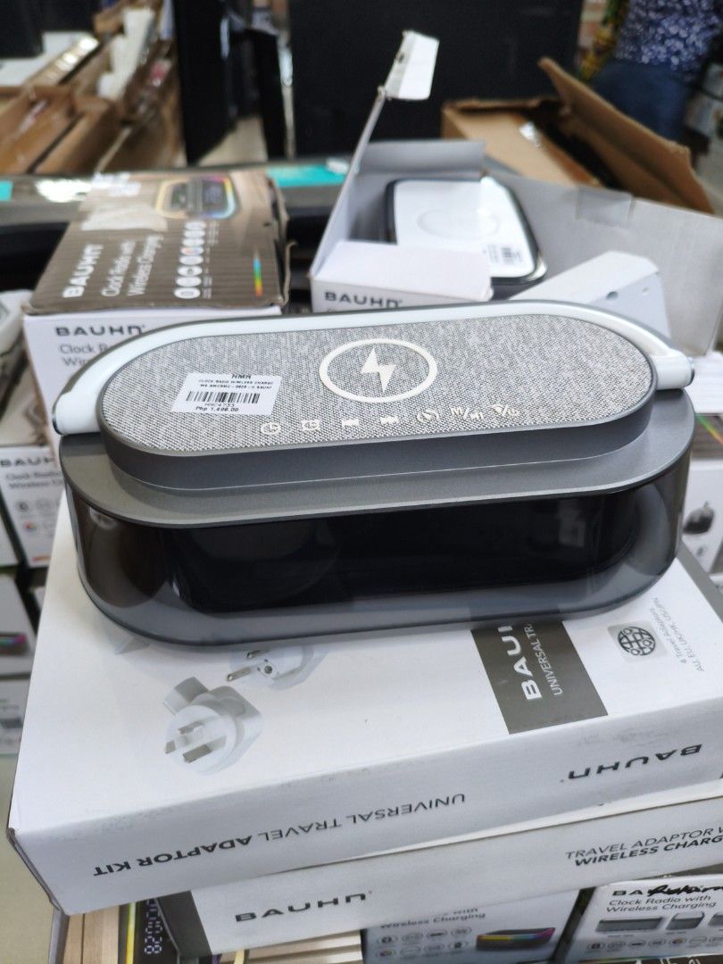 BAUHN Clock Radio with Wireless Charging (Category: Clocks) located in Manila. Submitted by hmrgrace5. (Listing ID 1431005012, Image 1). Description: BAUHN clock radio with wireless charging. Features Bluetooth, wireless charging, and a digital display. The box shows the clock radio with a colorful light display. Includes a universal travel adaptor kit. The clock radio has a sleek design with a built-in wireless charging pad..
