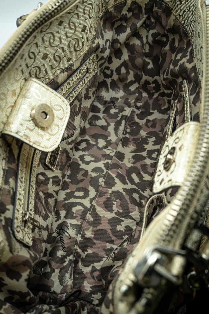 Guess Gold Handbag (Category: Shoulder Bags) located in Silang. Submitted by melstore (Listing ID 1431105706, Image 3). Description: PRE-LOVED ORIGINAL A Gold Guess handbag with a leopard print interior and a gold-toned hardware. Features a zippered closure and a magnetic snap closure on the front pocket. Interior includes a small zippered pocket. .