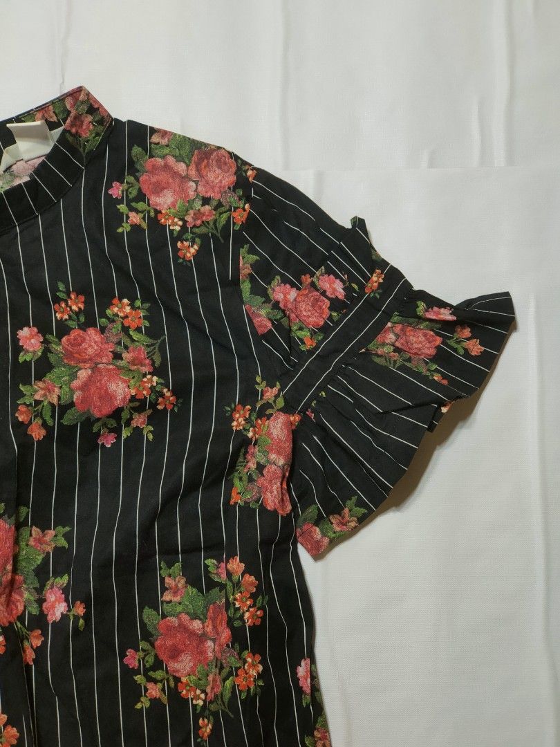 H&M Floral Striped Blouse Black (Category: Blouses) located in Marikina City. Submitted by styledandsassified (Listing ID 1431141378, Image 3). Description: H&M blouse features a black and white striped pattern with a floral design. It has short sleeves with ruffle details and a high neckline. The blouse has a split at the back. The tag indicates it is a size EUR 34..