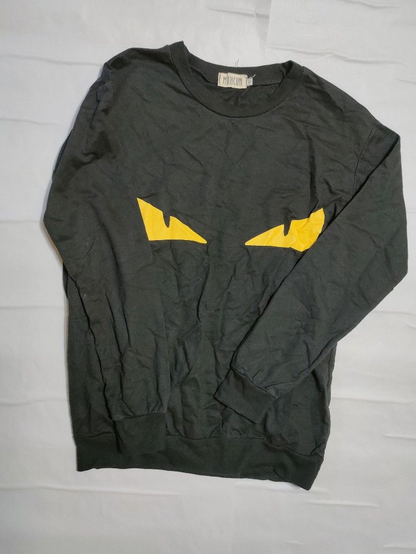 Muzicun Eye Graphic Sweatshirt (Category: Coats, Jackets and Outerwear) located in Marikina City. Submitted by styledandsassified (Listing ID 1431142420, Image 1). Description: Dark grey Muzicun sweatshirt featuring a yellow eye graphic on the front. It has a crew neck and long sleeves. The size tag indicates it is a size L. The Muzicun brand label is visible on the inside of the collar..