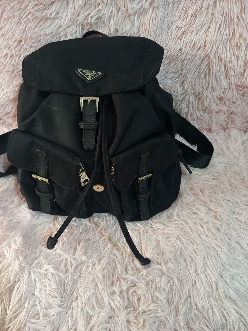 Sale Prada Black Backpack (Category: Luxury Bags & Wallets) located in Valenzuela. Submitted by cc850906 (Listing ID 1431177643, Image 3). Description: Black Prada backpack with multiple compartments and adjustable straps. Features a front flap with a buckle closure and the Prada logo. Includes side pockets with buckle details. The backpack has a drawstring closure and a top handle..