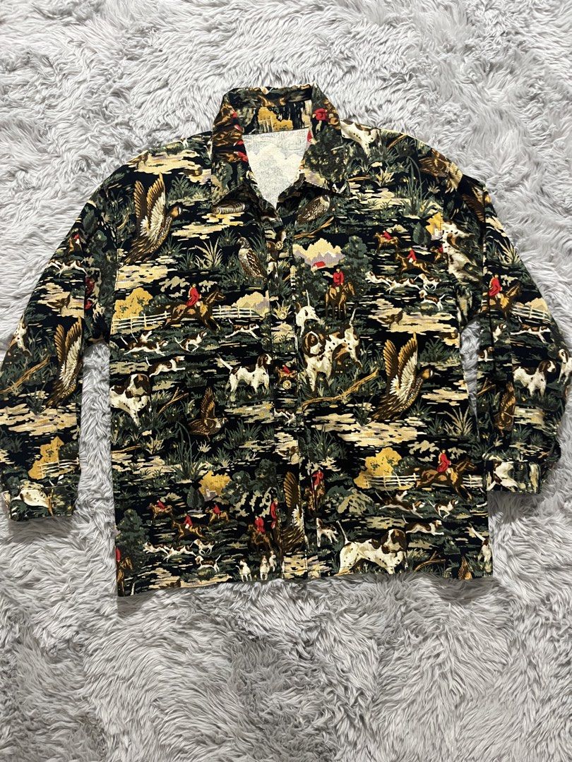 Vintage Hunting Print Button-Up Shirt (Category: Tshirts & Polo Shirts ) located in Taytay. Submitted by mc_marcy (Listing ID 1431000117, Image 1). Description: Vintage button-up shirt features a unique hunting scene print. It has long sleeves and a collared neckline. The shirt has a button-down closure and a classic fit. The print includes various animals and hunters in a landscape setting. Got this for 600.
