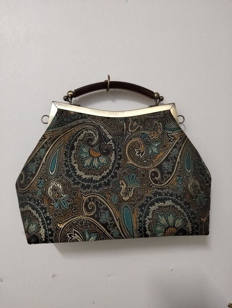 Vintage Paisley Handbag with Chain Strap (Category: Luxury Bags & Wallets) located in Gasan. Submitted by AngeliqueKaye (Listing ID 1420396040, Image 1). Description: - Vintage handbag - Unique paisley pattern (blue, brown, black) - Metal frame - Top handle - Detachable chain strap - Clasp closure - Light-colored interior lining - Small interior pocket - Metal accents.