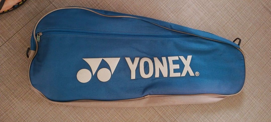 Yonex Badminton Racket Bag (Category: Racket and Ball Sports) located in Quezon City. Submitted by rominaa (Listing ID 1431026115, Image 2). Description: Yonex badminton racket bag. It is blue with a white Yonex logo. The bag has a zipper closure and a handle for carrying. The bag's exterior is blue and beige..