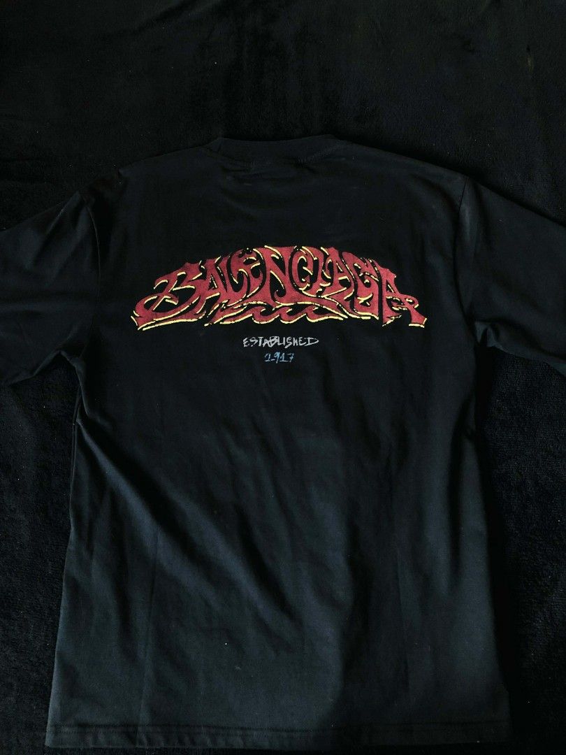 Balenciaga Graffiti Logo T-shirt (Category: Tshirts & Polo Shirts ) located in Cavite. Submitted by devetement (Listing ID 1435366237, Image 2). Description: - Balenciaga black t-shirt - Graffiti-style logo in red and yellow - Brand name on front and back - "ESTABLISHED 2017" detail - Crew neck style - Authentic with visible tag.