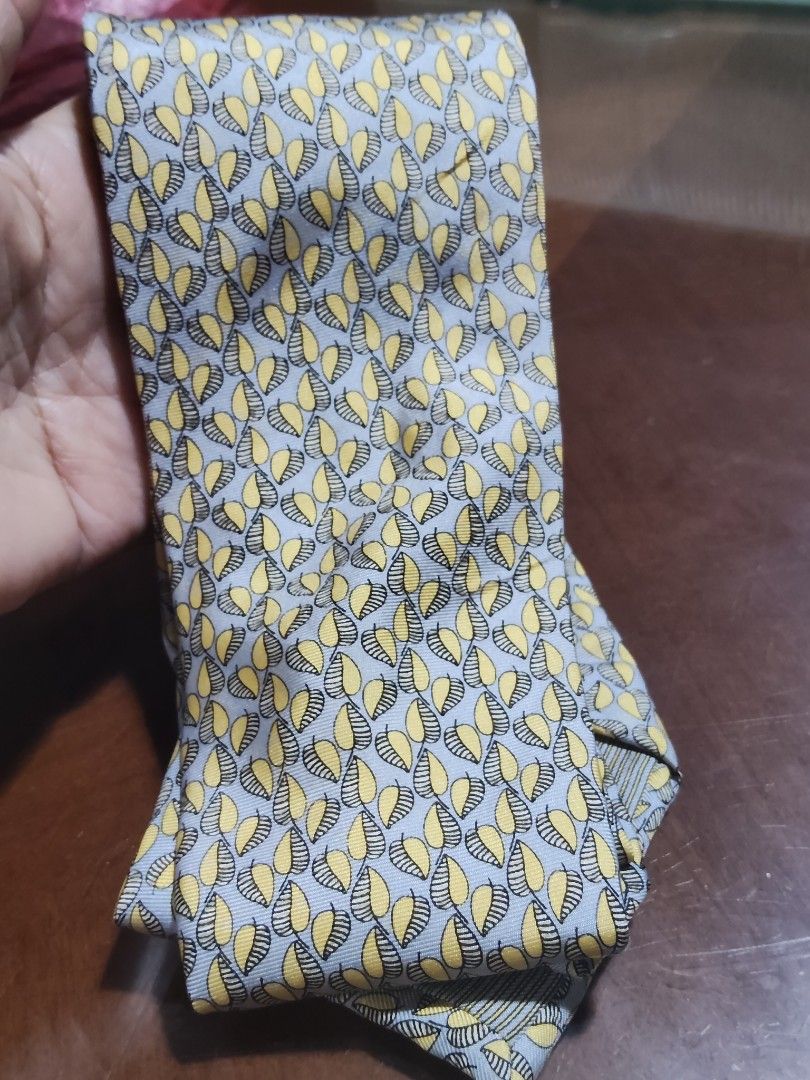 Dunhill London Silk Tie (Category: Ties) located in Cebu City. Submitted by almzcorner (Listing ID 1435415859, Image 2). Description: - Dunhill London tie - Silk material - Features a repeating leaf pattern in yellow and gray - Classic design - Confirmed authenticity with visible Dunhill label - Perfect for formal or semi-formal events.