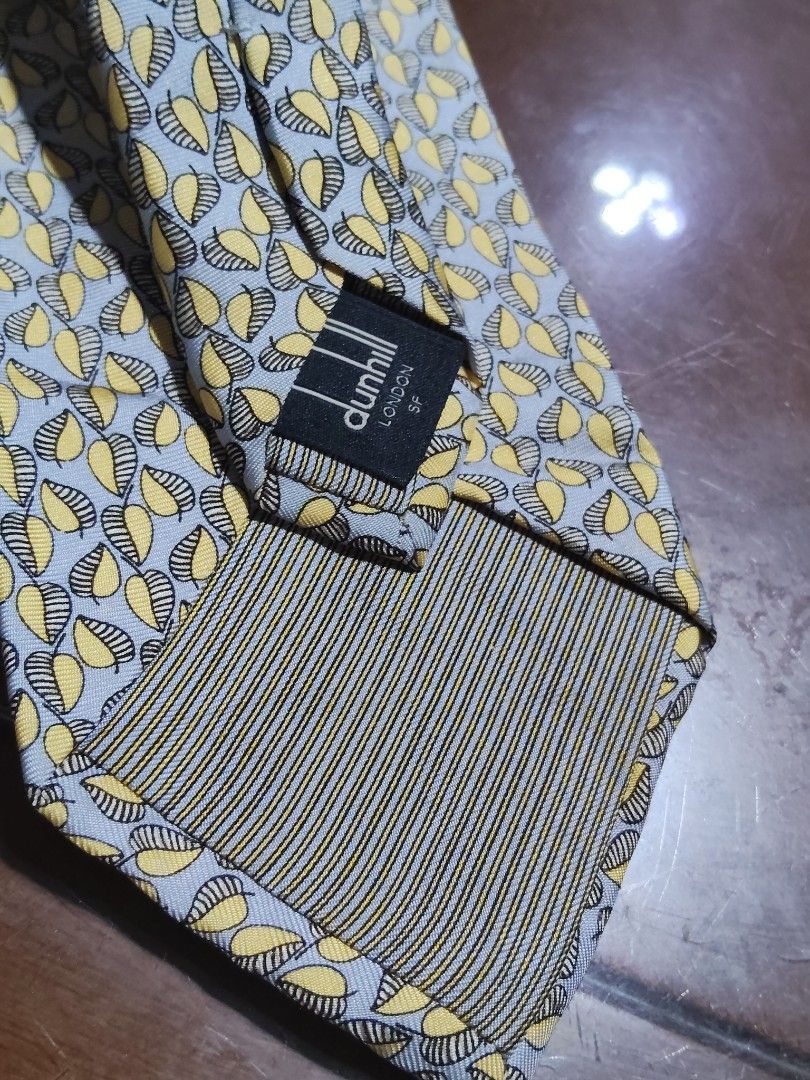 Dunhill London Silk Tie (Category: Ties) located in Cebu City. Submitted by almzcorner (Listing ID 1435415859, Image 3). Description: - Dunhill London tie - Silk material - Features a repeating leaf pattern in yellow and gray - Classic design - Confirmed authenticity with visible Dunhill label - Perfect for formal or semi-formal events.
