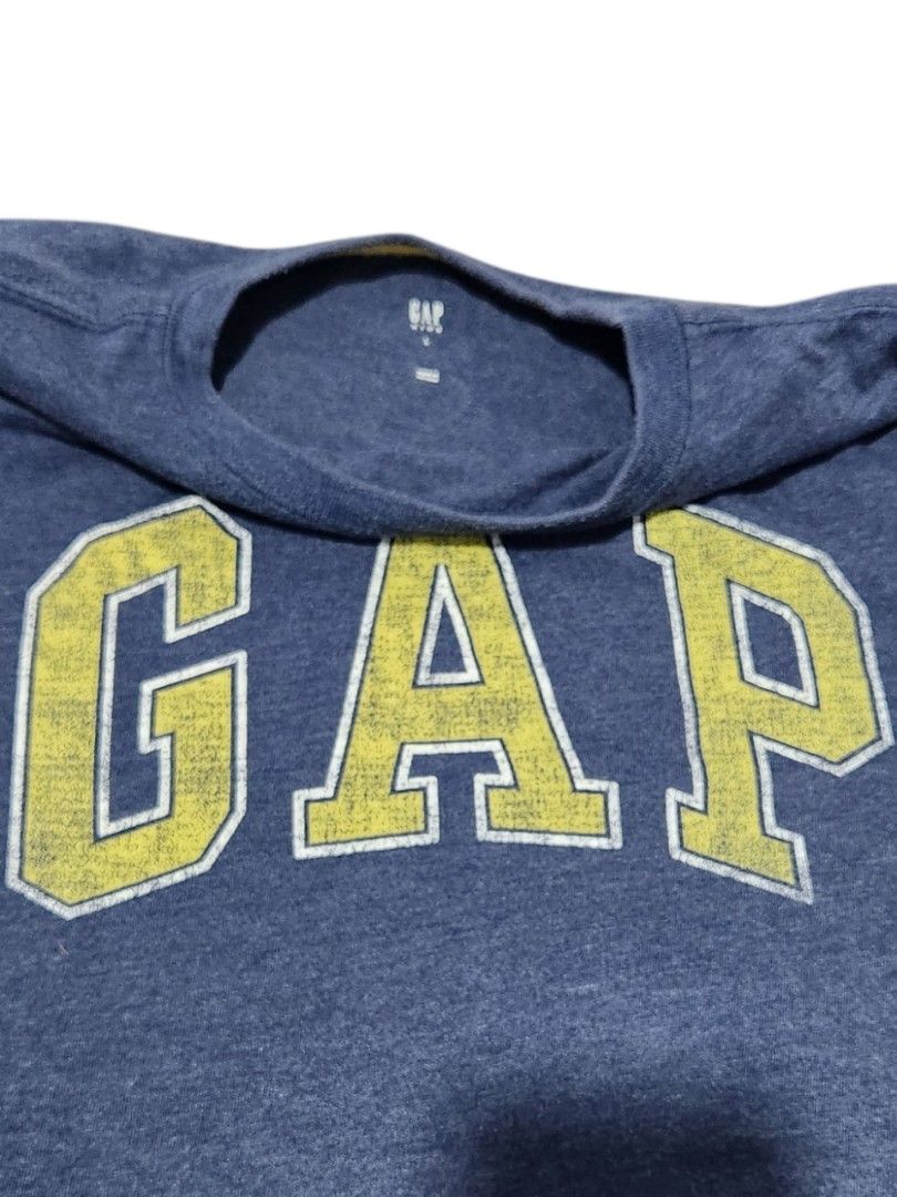 Gap T-shirt (Category: Babies & Kids Fashion) located in Paranaque City. Submitted by macadamia31 (Listing ID 1435463137, Image 2). Description: Gap T-shirt features a navy blue color with a yellow "GAP" logo on the front. It has a crew neck and short sleeves. It is a classic and versatile piece for everyday wear..