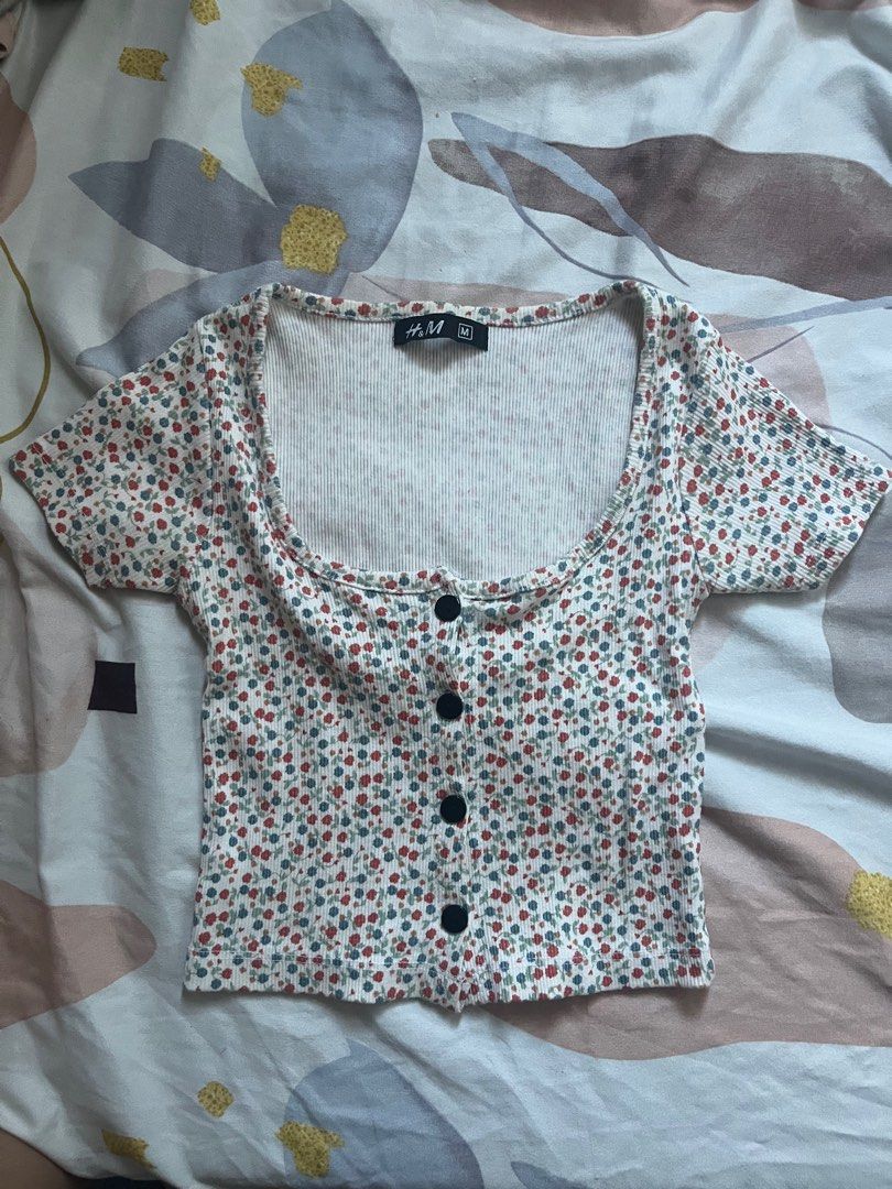 H&M Floral Button-Up Top - Size M (Category: Blouses) located in Paranaque City. Submitted by rieclutter (Listing ID 1435410066, Image 1). Description: - H&M floral top - Size: M - Features: - Button-up front - Scoop neckline - Short sleeves - Style: Cropped - Fabric: Ribbed - Color: White, red, and blue floral print.