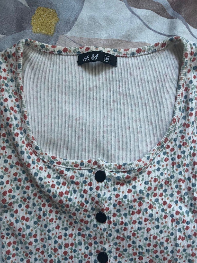H&M Floral Button-Up Top - Size M (Category: Blouses) located in Paranaque City. Submitted by rieclutter (Listing ID 1435410066, Image 2). Description: - H&M floral top - Size: M - Features: - Button-up front - Scoop neckline - Short sleeves - Style: Cropped - Fabric: Ribbed - Color: White, red, and blue floral print.