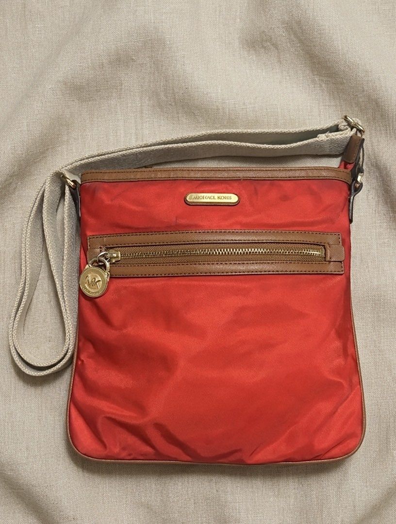 Michael Kors Nylon Crossbody Bag (Category: Cross-body Bags) located in Aparri. Submitted by lpenny (Listing ID 1435509888, Image 1). Description: - Michael Kors crossbody bag - Vibrant red nylon exterior - Brown leather trim - Gold-tone zipper - Signature MK logo - Adjustable strap - Red interior lining - Front zippered pocket - Main compartment (Needs cleaning).