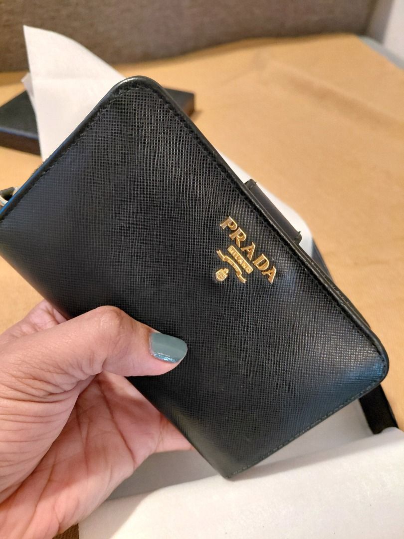 Prada Saffiano Leather Zip Wallet (Category: Luxury Bags & Wallets) located in Makati City. Submitted by jisla (Listing ID 1435510133, Image 1). Description: - Authentic Prada wallet - Black Saffiano leather - Gold-tone hardware - Prada logo - Zip closure - Includes box, authenticity card, and dust bag - Multiple compartments - Stylish and functional.