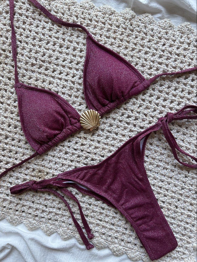 Shimmering Burgundy Bikini with Shell Detail (Category: Bikinis & Swimsuits) located in Cagayan de Oro. Submitted by elviecup (Listing ID 1435520695, Image 2). Description: Bikini set features a shimmering burgundy fabric. The top has triangle cups and a gold seashell accent. The bottoms are a thong style with tie sides. Both the top and bottom have tie closures for an adjustable fit. Perfect for a beach day or poolside lounging..