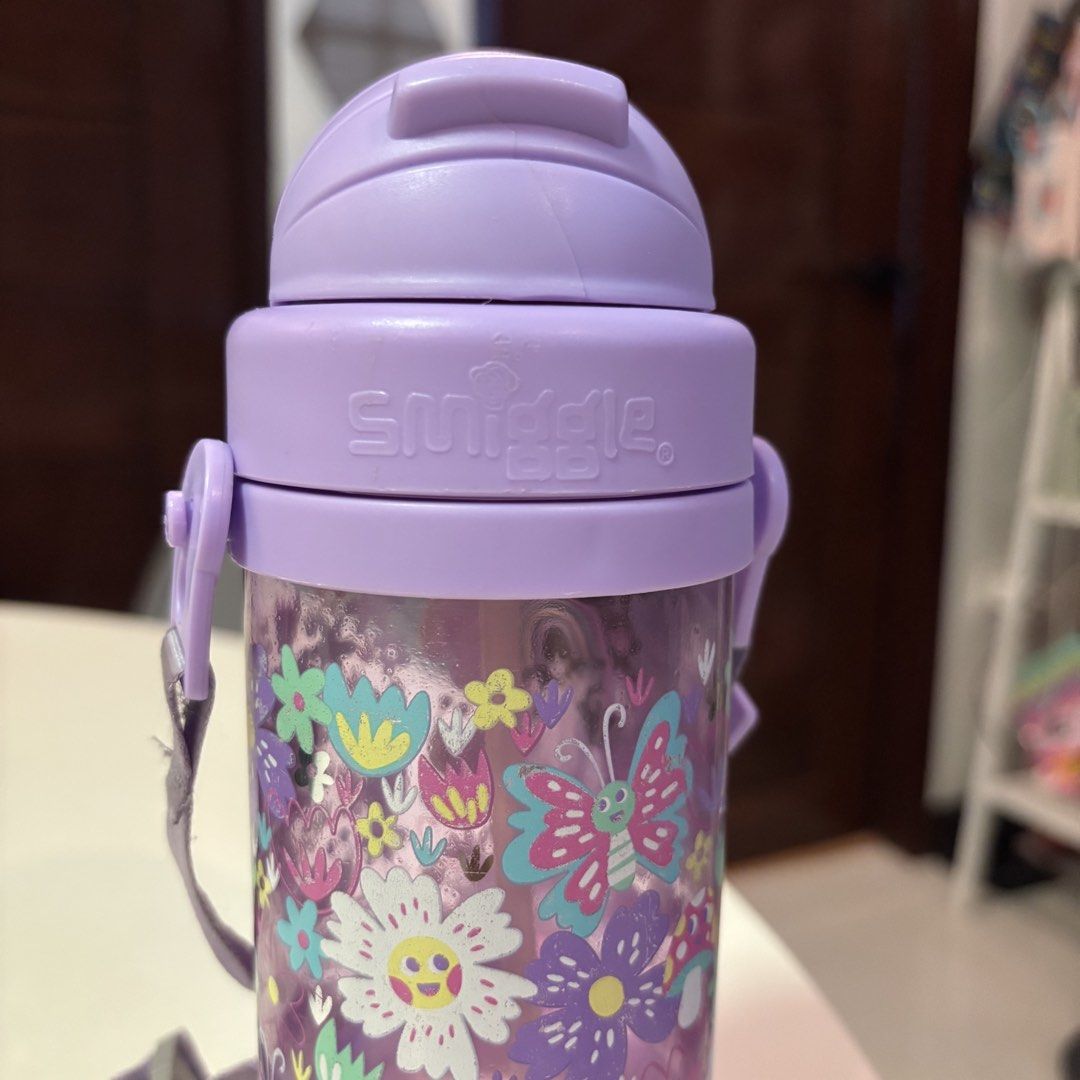 Smiggle Teeny Tiny Plastic Drink Bottle with Strap (Category: Water Bottles & Tumblers) located in Santa Rosa. Submitted by dawnardel16 (Listing ID 1435438162, Image 3). Description: - Smiggle Teeny Tiny Plastic Drink Bottle - Features a colorful floral design - Comes with a purple lid and strap - Secured lid for spill-proof use - Smiggle logo is visible Issues (see photos): - Straw needs to be replaced - cracked lid/cover but can still be used (