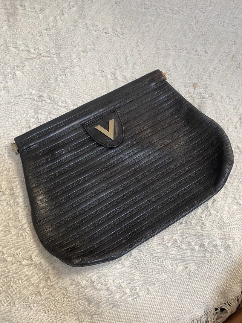 Valentino Black Clutch Bag (Category: Clutches) located in Naga. Submitted by ejdurante17 (Listing ID 1435413872, Image 1). Description: - Valentino black clutch bag - Textured design - Valentino name embossed - Metal V logo on front - Made in Italy - Fold-over flap - check last pic for issue ( inner) MOP: GCASH / BDO / MAYA PAYMENT FIRST ‼️ NO COD 🚫 J&T Door to Door delivery.