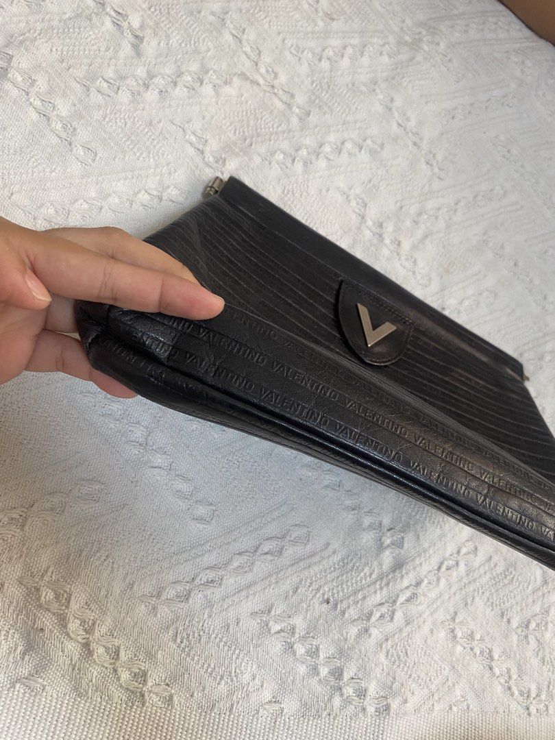 Valentino Black Clutch Bag (Category: Clutches) located in Naga. Submitted by ejdurante17 (Listing ID 1435413872, Image 3). Description: - Valentino black clutch bag - Textured design - Valentino name embossed - Metal V logo on front - Made in Italy - Fold-over flap - check last pic for issue ( inner) MOP: GCASH / BDO / MAYA PAYMENT FIRST ‼️ NO COD 🚫 J&T Door to Door delivery.
