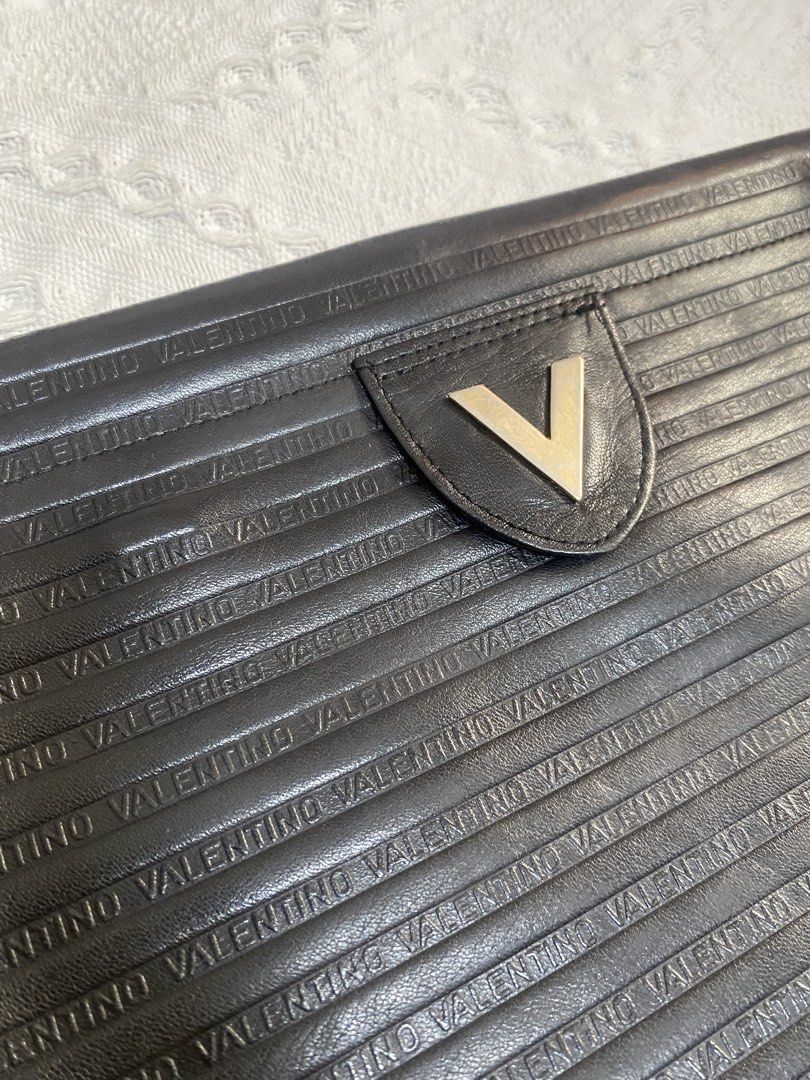 Valentino Black Clutch Bag (Category: Clutches) located in Naga. Submitted by ejdurante17 (Listing ID 1435413872, Image 2). Description: - Valentino black clutch bag - Textured design - Valentino name embossed - Metal V logo on front - Made in Italy - Fold-over flap - check last pic for issue ( inner) MOP: GCASH / BDO / MAYA PAYMENT FIRST ‼️ NO COD 🚫 J&T Door to Door delivery.