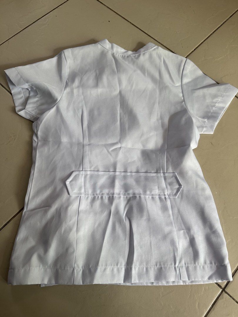 White Medical Uniform Top (Category: Blouses) located in Manila. Submitted by rachael_23 (Listing ID 1435348632, Image 3). Description: - White medical uniform top - Short sleeves - Mandarin collar - Button-up closure - Chest pocket - Small emblem - Decorative back panel - Ideal for medical professionals and students.