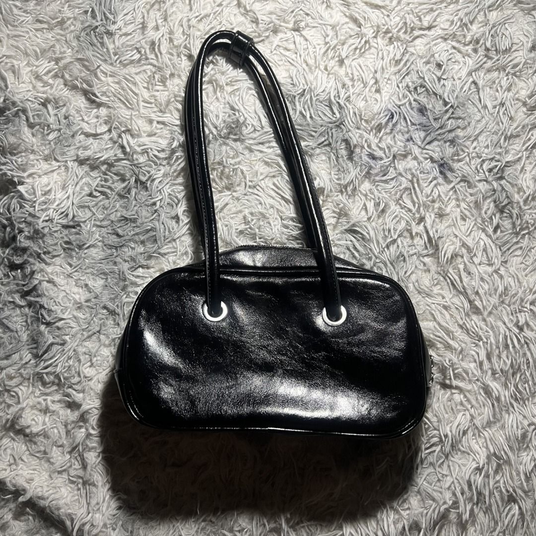 Y2K Glossy Bowler Bag (Black) (Category: Luxury Bags & Wallets) located in Cagayan de Oro. Submitted by ogvarieties (Listing ID 1435462607, Image 2). Description: Model Style: "East-West" Mini Bowler (wider than it is tall). Product Details: - Y2K / Minimalist Vintage. - Jet black faux leather with a high-gloss, "patent" look and a slight wrinkled texture. - Distinctive silver-toned grommets where the straps meet the bag. -Double slim shoulder st