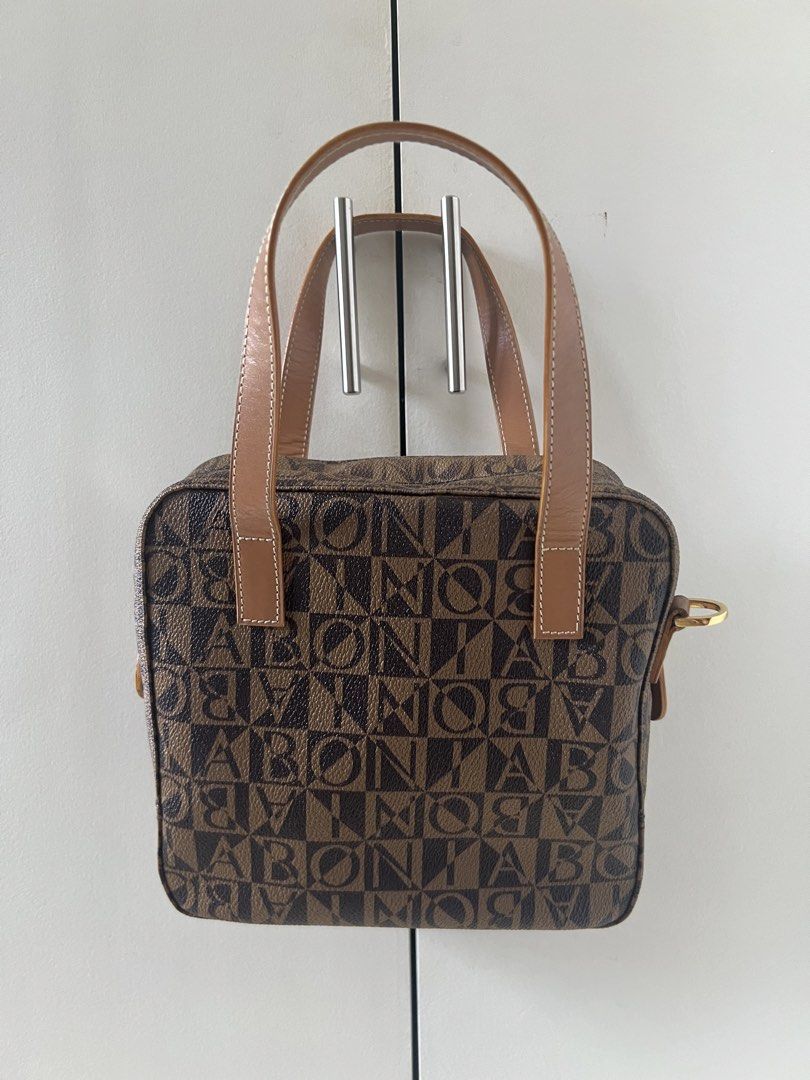 Bonia Brown Handbag (Category: Luxury Bags & Wallets) located in Manila. Submitted by rhearhea17 (Listing ID 1437172861, Image 1). Description: - Bonia handbag - Brown color with repeating logo pattern - Zip closure - Multiple interior compartments - Rectangular shape, structured design - Gold-toned hardware - Two top handles - Lighter brown handles and trim Faults: - Zipper leather handle needs to be glued - Leather has some whiter spots.