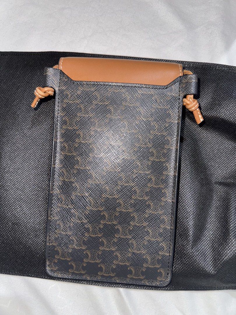 Celine Triomphe Phone Pouch (Category: Luxury Bags & Wallets) located in Quezon City. Submitted by jdmc16 (Listing ID 1437144484, Image 2). Description: - Celine Triomphe phone pouch - Color: Brown and Black - Features flap closure with Celine logo - Drawstring closure - Brown leather top - Black and brown patterned body - Includes dust bag.