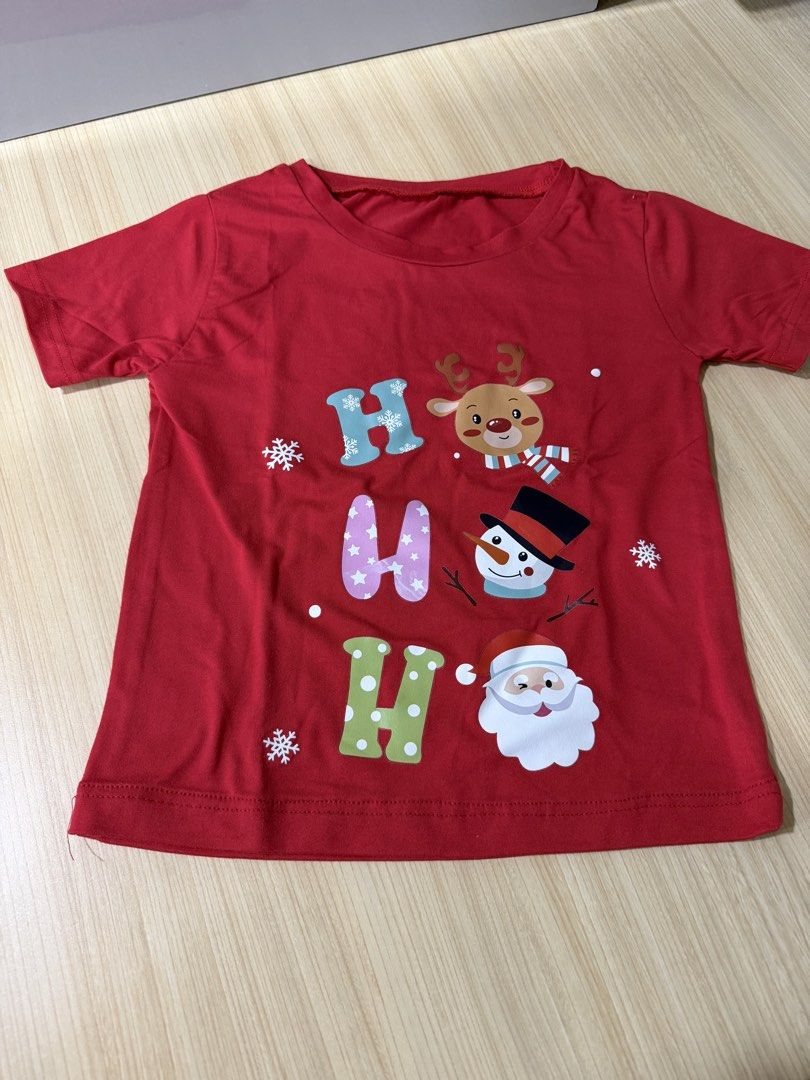 Christmas Red T-shirt (Category: Babies & Kids Fashion) located in Mandaluyong City. Submitted by jpc0708 (Listing ID 1437135573, Image 1). Description: - Red Christmas t-shirt - Features "HO HO HO" design with reindeer, snowman, and Santa Claus - Short sleeves - Round neckline - Measurements: Approximately 17 inches length x 13 inches width - Plain red back.